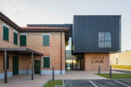 Vista frontale dei nuovi uffici Ricci Casa a Bologna con facciata in vetro e mattoni a vista, edificio moderno su preesistente 