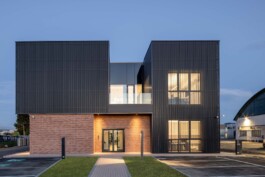 Gli uffici Ricci Casa illuminati di sera con facciata trasparente 